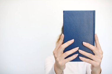 Genç bir kız elinde bir kitap tutuyor.