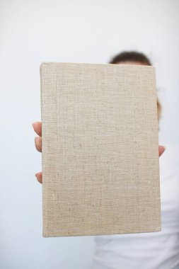 Genç bir kız elinde bir kitap tutuyor.