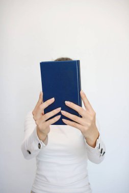 Genç bir kız elinde bir kitap tutuyor.