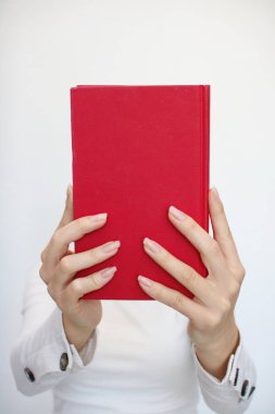 Genç bir kız elinde bir kitap tutuyor.