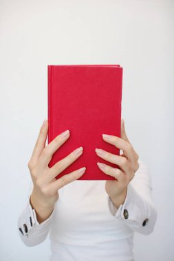 Genç bir kız elinde bir kitap tutuyor.