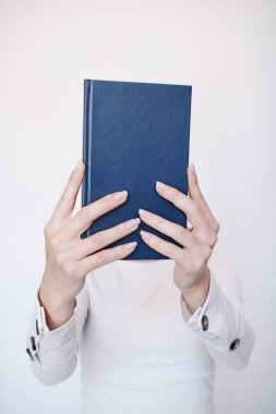 Genç bir kız elinde bir kitap tutuyor.