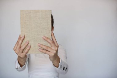 Genç bir kız elinde bir kitap tutuyor.