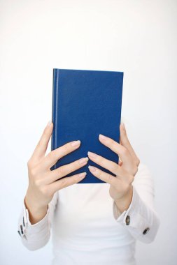 Genç bir kız elinde bir kitap tutuyor.