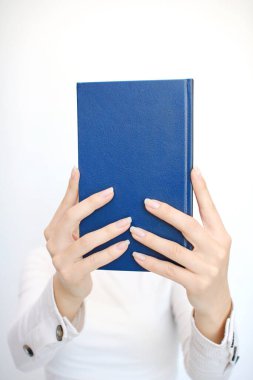 Genç bir kız elinde bir kitap tutuyor.