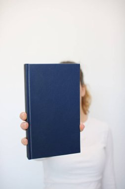 Genç bir kız elinde bir kitap tutuyor.