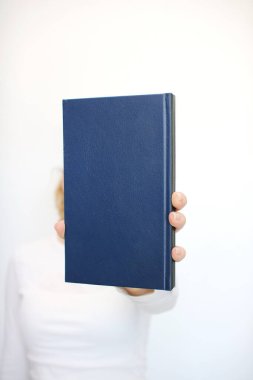 Genç bir kız elinde bir kitap tutuyor.