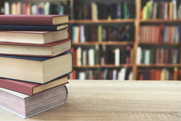 Ahşap masanın üzerindeki kitap yığını tuğla duvar zeminine karşı