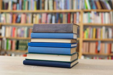 Tahta bir masanın arka planında arka arkaya dizilmiş kitaplar. Beyaz arka plan, eğitim, okuma, yüksek kaliteli kitaplar, okul, kütüphane, William Shakespeare, edebiyat, 