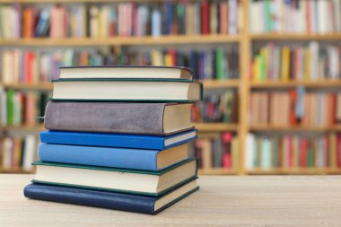 Tahta bir masanın arka planında arka arkaya dizilmiş kitaplar. Beyaz arka plan, eğitim, okuma, yüksek kaliteli kitaplar, okul, kütüphane, William Shakespeare, edebiyat, 