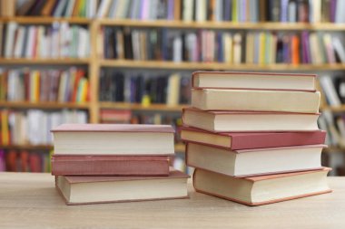 Ahşap masanın üzerinde bulanık arka plana karşı bir yığın kitap. Metin için boşluk