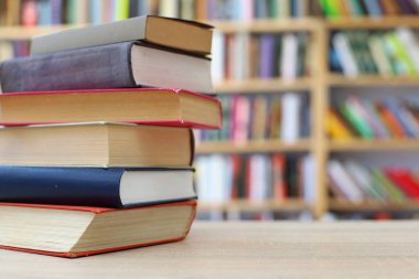 Tahta masanın üzerinde bir yığın kitap var.