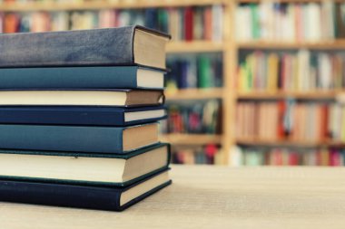 Kütüphanedeki ahşap masada yığınla kitap.