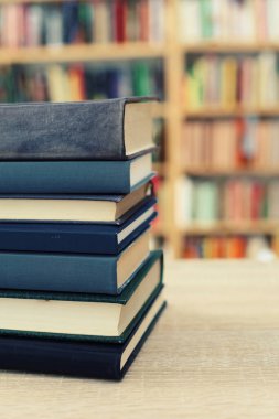 Tahta masadaki yığının önünde bir kitap yığını