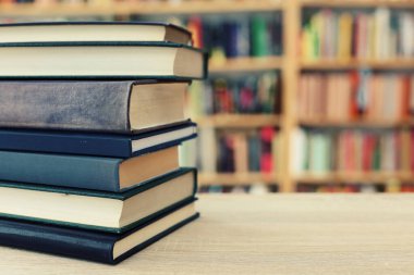 Tahta bir masada yığınla kitap.