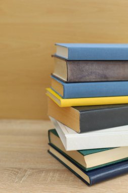 Tahta masadaki kitap yığını beyaz arka plana karşı. Metin için boşluk