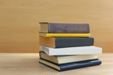 Ahşap masanın üzerinde bulanık arka plana karşı bir yığın kitap. Metin için boşluk