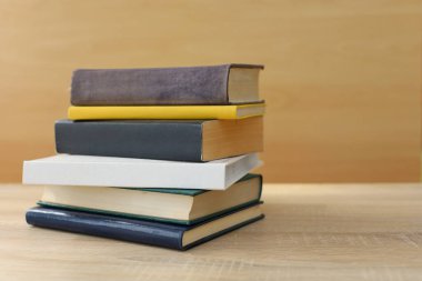 Kütüphanedeki ahşap masada yığınla kitap.