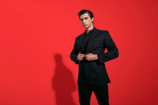 Handsome young man in black suit over red background. Horizontal view. — Stock Photo, Image