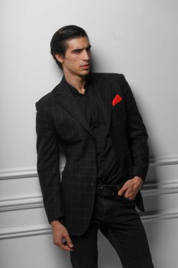 Siyah takım elbiseli, beyaz arka planda kırmızı ipek eşarplı çekici bir gencin dikey portresi..