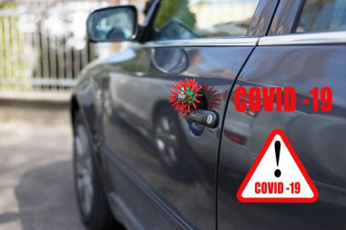 Üzerinde COVID-19 yazan kırmızı başlık beyaz üçgen üzerinde soyut virüs türü modeli aracın kapısında duruyor..