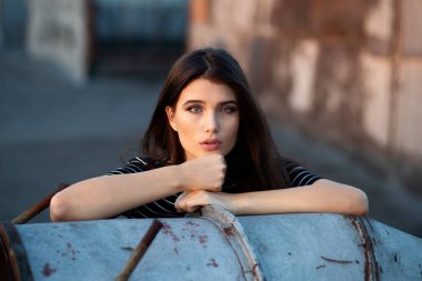 Hippi, kendine güvenen güzel gözlü ve düz saçlı genç bir kız. Gün batımında çatıda kameraya bakıyor..