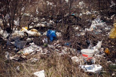 Yatay görüş. Çöp, plastik, torbalar ve polyester saçılmış ve gün ışığında kuru çimlere atılmış. Ekoloji kavramı, doğaya kayıtsızlık.