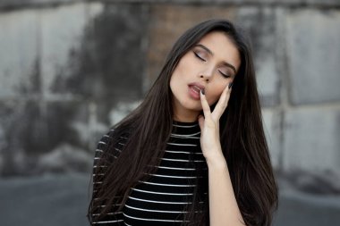 Yatay görüş. Şehvetli, rüya gören, düz esmer saçlı, modern kıyafetler giymiş, makyajlı, siyah tırnaklı, gözleri kapalı bir kızın güzel portresi..