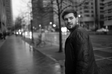 Yakışıklı genç adam sokakta yürüyor, yağmurda geri dönüyor.