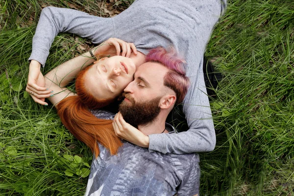 Vista superior de um casal hipster, sentado em uma grama, sentado com as cabeças viradas com os olhos fechados . — Fotografia de Stock