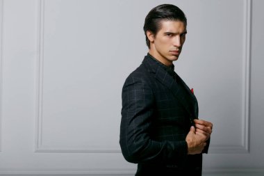 Siyah takım elbiseli yakışıklı bir adamın yatay portresi cebinde kırmızı ipek bir eşarp, beyaz arka planda poz veriyor..