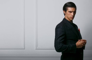 Siyah takım elbiseli, beyaz arka planda kırmızı ipek eşarplı yakışıklı bir adamın profil portresi..