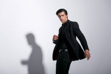 Beyaz arka planda siyah takım elbiseli yakışıklı esmer adam. Yatay görüş. Boşluğu kopyala.