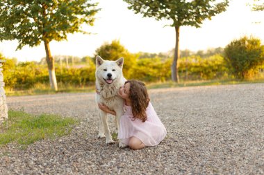 Sevimli küçük bir kızın uzun bir portresi yazın birlikte dışarıda vakit geçiren büyük köpeğine sarılıyor. Metin için boşluk.