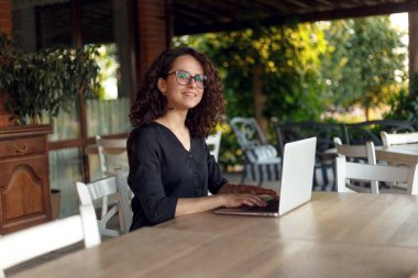 Bilgisayarla çevrimiçi çalışırken Not Defteri Klavyesinde yazan Güzel Neşeli Kadın Portresi. Terasta Oturan Kadın .