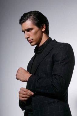 Beyaz arka planda siyah giysili yakışıklı bir gencin profili. Dikey görünüm.