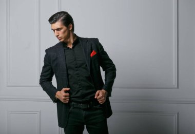 Siyah takım elbiseli, beyaz arka planda kırmızı ipek eşarplı özgüvenli bir gencin portresi. Yatay görünüm.