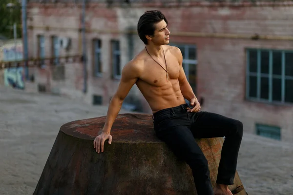 Schöner muskulöser und fitter, sportlicher junger Mann mit nacktem Oberkörper, bekleidet mit schwarzen Jeans, posiert auf alter, verlassener Fabrik. — Stockfoto