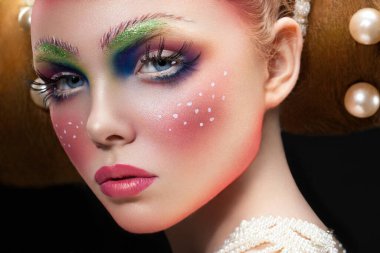 Yaratıcı peri makyajlı beyaz bir kadın modelin yakın plan portresi, kameraya bakıyor..