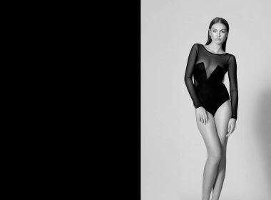 Uzun saçlı ve makyajlı çekici bir genç kadının ön portresi. Siyah bir elbise giyip kameraya bakıyor. Mesaj için yer var. Siyah beyaz fotoğraf.