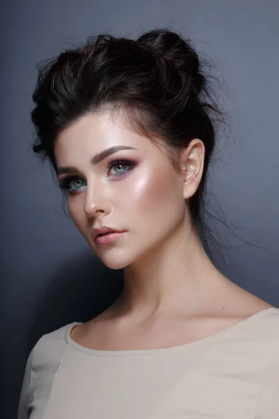 Gri arka planda izole edilmiş, muhteşem makyajlı güzel bir esmer model portresi. Dikey stüdyo çekimi.