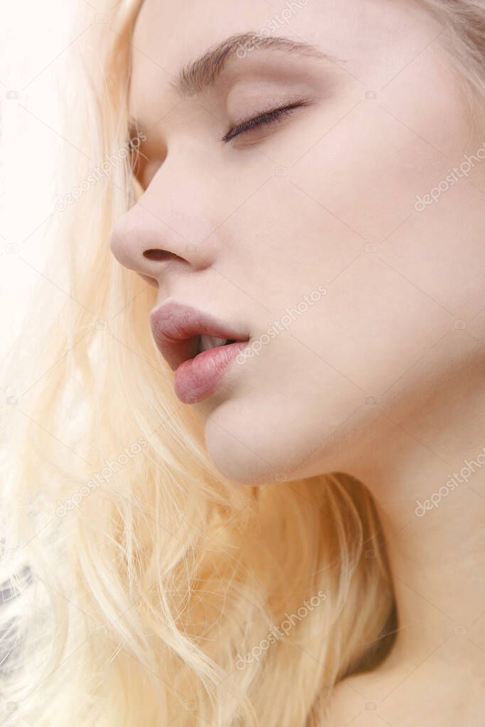 Closeup portrait of young beautiful blond woman face posing with closed eyes.