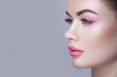 Gri arka planda makyajlı kadın yüzü profili.