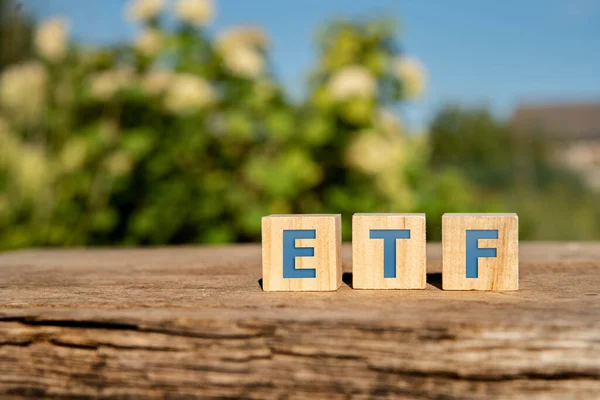 ETF, Exchange Traded Fund concept, cube wooden block with alphabet building the word ETF at the center on green background