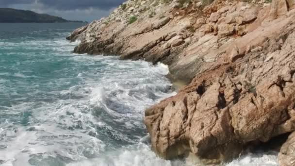 石のビーチで波が砕け スプレーを形成する 岩の上に波が打ち寄せる映像 — ストック動画