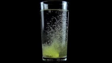 C vitamini tableti şeffaf bir cam bardağa suyla atılır. Fışkırtan Sarı