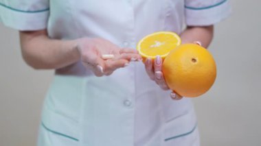 Beslenme uzmanı Doktor Sağlıklı Yaşam Tarzı Konsepti - Vitamin Hapı ve Portakal Meyvesi Tutma 