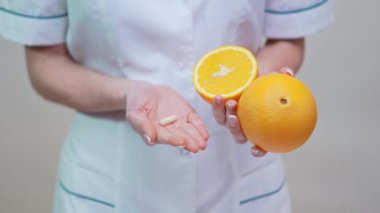 Beslenme uzmanı Doktor Sağlıklı Yaşam Tarzı Konsepti - Vitamin Hapı ve Portakal Meyvesi Tutma 