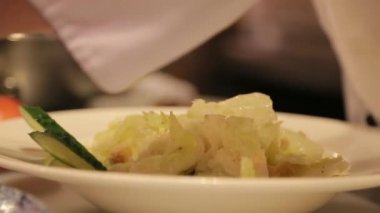 Şef salatayı Chiken dilimleriyle süslüyor.