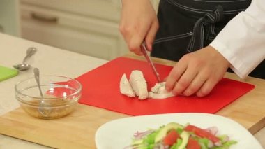 Şef salata için haşlanmış tavuk filetosu kesiyor.